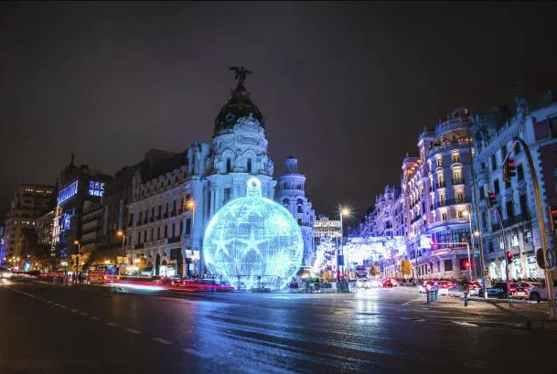 Gran Vía de Madrid iluminada por la noche, con tiendas donde se puede comprar tinta y tóner de impresora.
